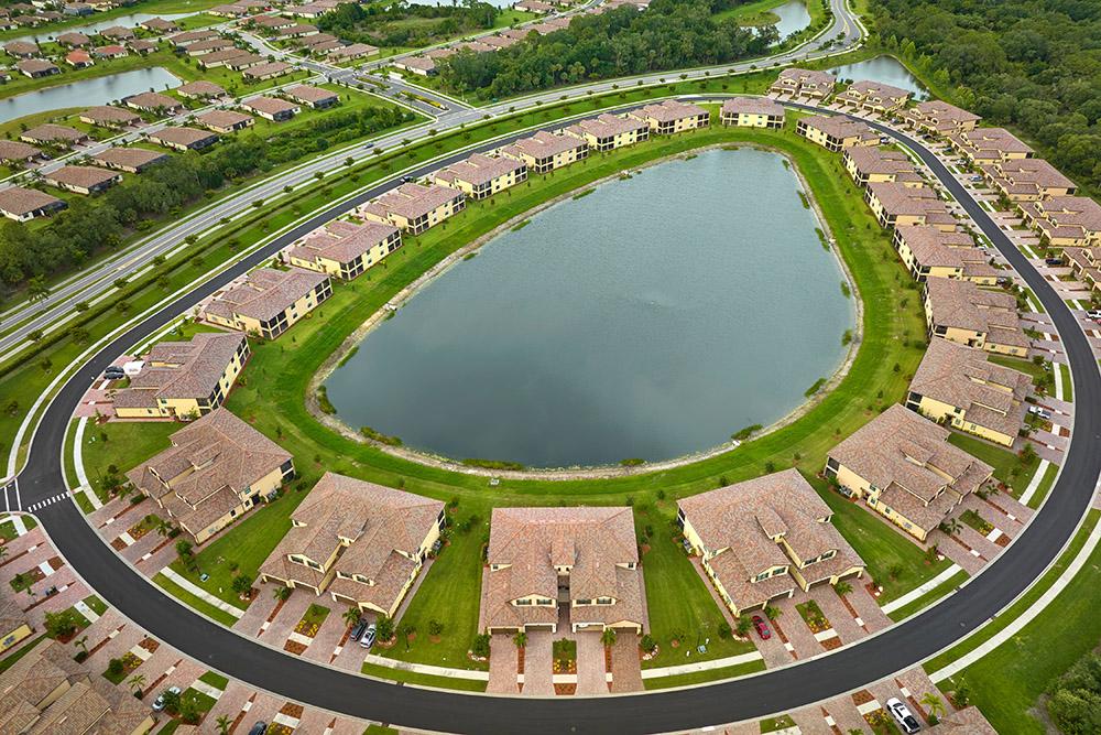 Aerial view of tightly located family houses with retention ponds to prevent flooding in Florida closed suburban area. Real estate development in american suburbs